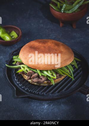 Hamburger chilien latino-américain Chacarero avec tranches de bœuf de qualité supérieure et haricots verts sur fond noir. Banque D'Images