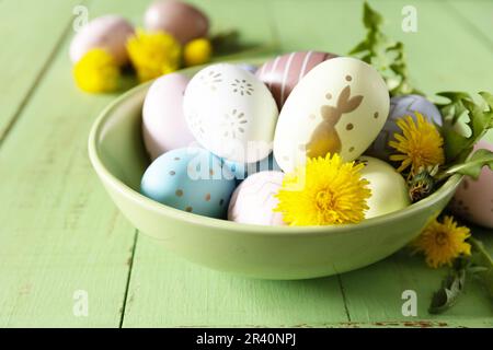 Joyeuses Pâques. Des œufs de Pâques faits main colorés et des fleurs de printemps dandelions sur une table rustique en bois. Composition de Pâques. Banque D'Images