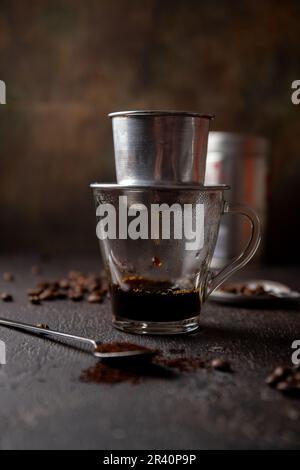 Préparation du café vietnamien avec l'aluminium cofe filer sur fond sombre Banque D'Images