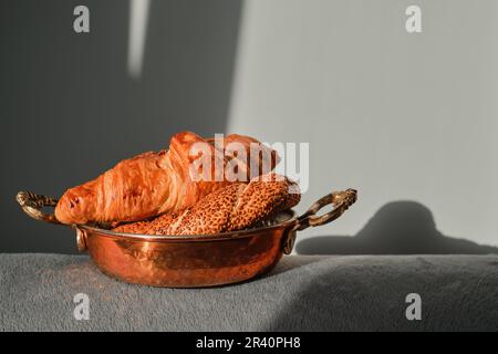 Pâtisseries fraîches pour le petit-déjeuner, croissants et bagels turcs aux graines de sésame, servis dans un plateau en cuivre sur la table. Pâte fraîche du matin. Banque D'Images