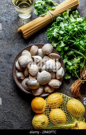 Ingrédients pour la préparation spaghetti aux palourdes - palourdes fraîches crues, spaghetti coriandre, vin blanc citron Banque D'Images