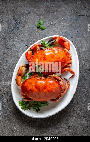 Les crabes entier cuit sur plaque blanche avec du citron et de la bière. Arrière-plan de béton gris. Vue d'en haut Banque D'Images