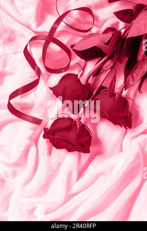 Cadeau romantique roses rouges sur le lit. Plan d'agencement avec vue de dessus. Copier l'espace. Couleur tendance de l'année 2023 - Viva Magenta. Banque D'Images