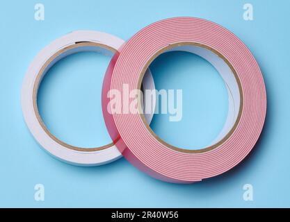 Deux rouleaux de ruban adhésif double face sur fond bleu, vue de dessus Banque D'Images