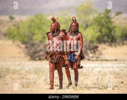Deux femmes de la tribu Himba marchent dans le désert en vêtements nationaux. Banque D'Images