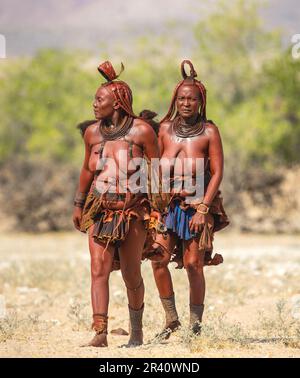 Deux femmes de la tribu Himba marchent dans le désert en vêtements nationaux. Banque D'Images