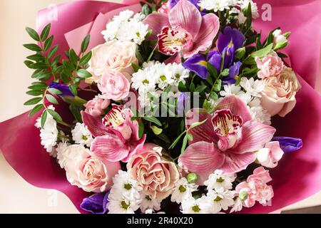 Carte de fête des mères, de fête des femmes ou d'anniversaire. Magnifique bouquet d'orchidées en fleurs, d'œillets et d'iris et de verdure printanière sur un Banque D'Images