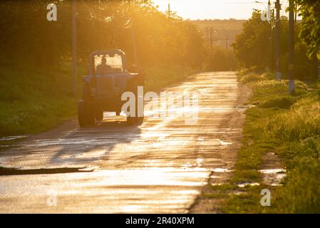 Scènes rurales de travaux agricoles avec des tracteurs conduisant des promenades dans la rue sur la route asphaltée dans la campagne de lumière du soleil Moldavie Banque D'Images