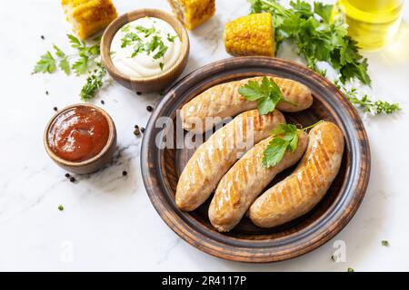 Menu de grillades. Repas de fête d'été. Saucisses grillées aux herbes fraîches et aux épices sur une table en marbre. Banque D'Images