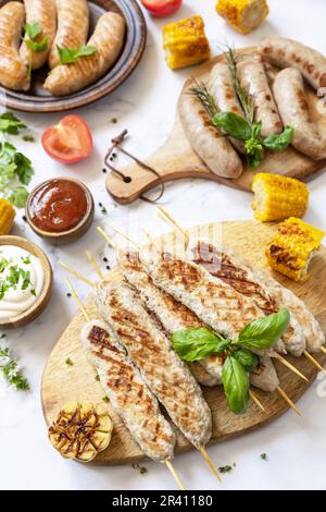 Repas de fête d'été. Menu de grillades. Barbecue de poulet grillé kebab avec des herbes fraîches et des épices sur une table en marbre. Banque D'Images