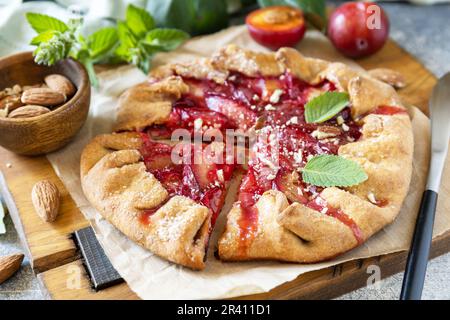 Galette prune. Tarte aux fruits à la baleine maison saine (galette) avec prunes et amandes, dessert végétarien végétalien sur une table en pierre. Banque D'Images