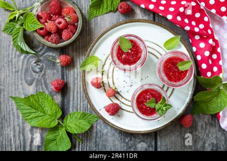 Petit déjeuner sain. Pots en verre avec pudding au chia à la framboise et à la confiture ou smoothies aux graines de chia sur table rustique. Vue depuis un Banque D'Images
