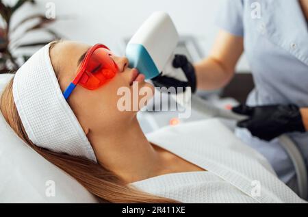 Jeune femme qui reçoit une épilation photo lors d'une visite au centre de beauté dans un salon de beauté Banque D'Images