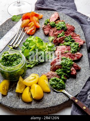 Tranches de steak de boeuf avec sauce au chimmichuri sur plaque de pierre grise Banque D'Images