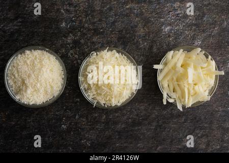 Parmesan fraîchement râpé et râpé dans des bols de préparation en verre : trois textures différentes de parmesan râpé et râpé vues d'en haut Banque D'Images