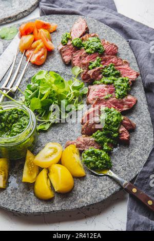 Tranches de steak de boeuf avec sauce au chimmichuri sur plaque de pierre grise Banque D'Images