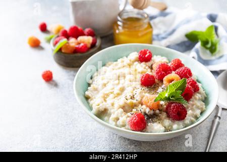 Porridge de flocons d'avoine dans un bol en céramique décoré de framboises fraîches et de graines de chia servies avec du miel. Un régime alimentaire sain breakfa Banque D'Images