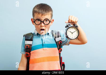 Enfant émerveillé dans les verres écouter le réveil sonnant montrant l'heure, étonnement Banque D'Images