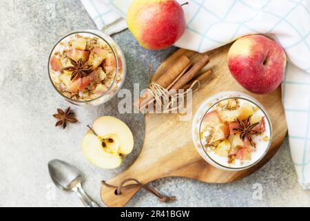 Dessert maison avec yaourt, granola, pommes au caramel et cannelle sur une table en pierre. Granola de petit déjeuner sain, vie saine Banque D'Images