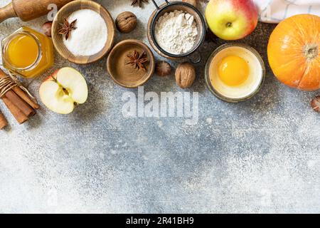 Fond de cuisson des aliments. Citrouilles, pommes, miel, noix et épices de saison pour la citrouille ou la tarte aux pommes sur un plan d'examen gris. Vue de Banque D'Images