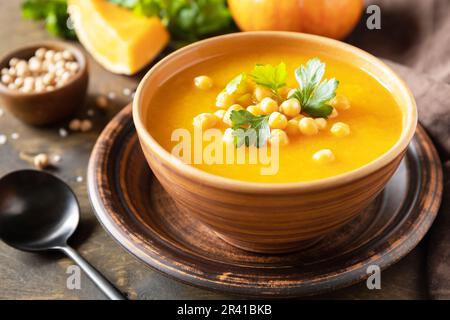 Soupe végétarienne à la crème de potiron et de pois chiches sur une table rustique en bois. Nourriture de confort, l'automne et l'hiver concept de nourriture lente saine. Banque D'Images