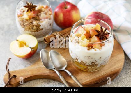 Dessert maison avec yaourt, granola, pommes au caramel et cannelle sur une table en pierre. Granola de petit déjeuner sain, vie saine Banque D'Images