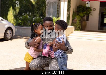 Père soldat de l'armée afro-américaine embrassant de jolis enfants à l'extérieur de la maison Banque D'Images