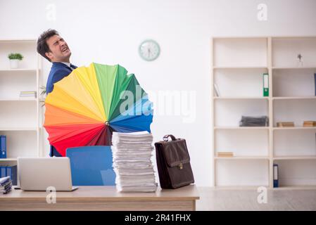 Jeune homme tenant un parapluie dans le bureau Banque D'Images
