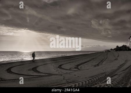 L'homme marche sur la plage avec des bâtons de marche nordique Banque D'Images