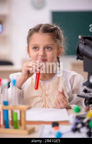 Petite fille étudiant la chimie dans la salle de classe Banque D'Images