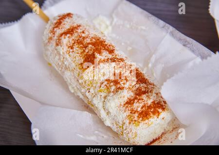 Elotes elote maïs Street food plat mexicain fromage cotija poudre épicée de piment sur un plat blanc Banque D'Images
