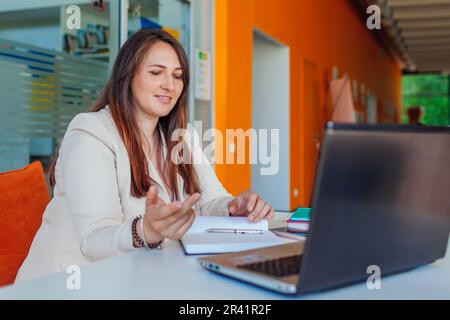 Jeune femme d'affaires enseignant tuteur parlant aux étudiants cowokers dans le chat en ligne par vidéoconférence sur ordinateur portable Banque D'Images
