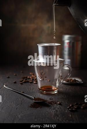 Préparation du café vietnamien avec l'aluminium cofe filer sur fond sombre Banque D'Images