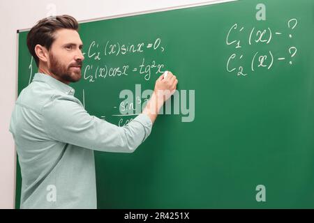 Professeur mature expliquant les mathématiques au tableau noir en classe Banque D'Images