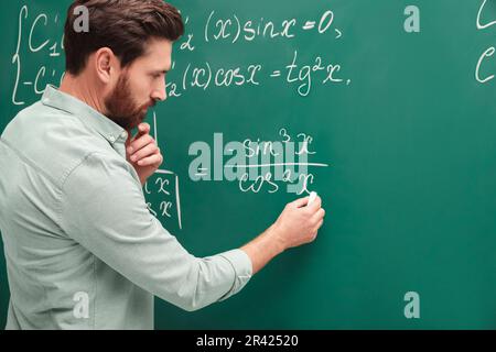 Professeur mature expliquant les mathématiques au tableau noir en classe Banque D'Images