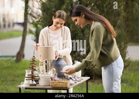 Les femmes magasinent à la table dans la cour. Vente de garage Banque D'Images