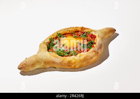 Adjarian khachuri sur fond blanc. Une version non conventionnelle de la cuisine géorgienne, un bateau à pâte avec du fromage, des tomates, des herbes Banque D'Images