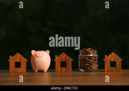 Tirelire, pot de pièces et modèles de maison sur table en bois Banque D'Images