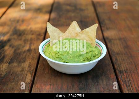 Délicieux guacamole fait d'avocats avec nachos sur table en bois Banque D'Images