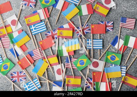De nombreux petits drapeaux en papier de différents pays sur table grise, à plat Banque D'Images