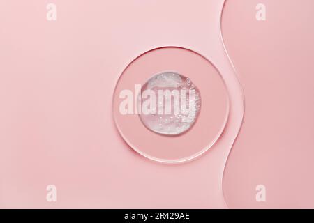 Boîte de Petri ronde avec produit cosmétique gel et lame en verre ondulé sur fond rose Banque D'Images
