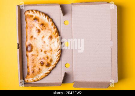 Fermeture de la zone de pizza dans une boîte d'emballage sur fond jaune Banque D'Images