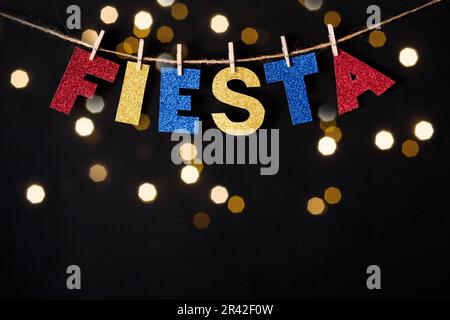 Fiesta Word fait de papier brillant et des épingles sur fond noir et des lumières de bokeh. Concept Cinco de mayo Banque D'Images