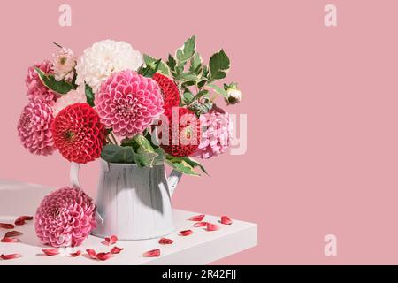 Bouquet d'automne de belles fleurs dahlias et pétales sur table blanche. Décoration automnale dans des tons roses, vue isométrique Banque D'Images