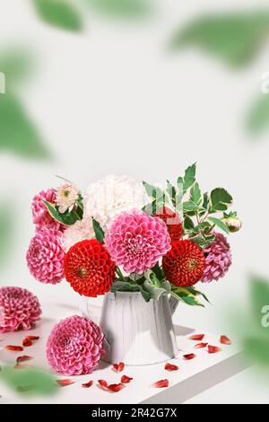 Bouquet de belles fleurs dahlias et pétales sur table blanche. Décoration automnale festive, vue isométrique Banque D'Images