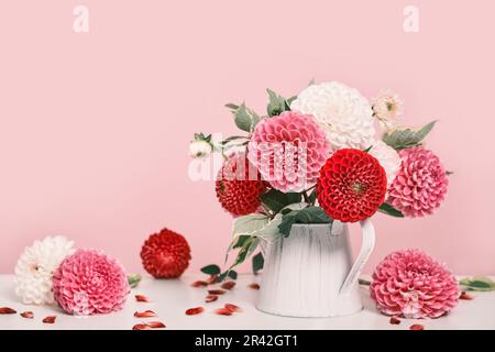 Bouquet de belles fleurs dahlias et pétales sur table blanche. Décoration automnale festive, ombres à la mode Banque D'Images