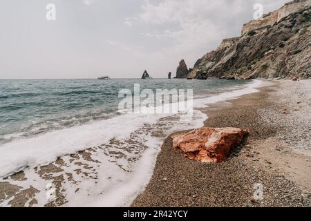 Grand rocher rouge de jasper sur la plage, avec la mer en arrière-plan. Gros plan sur Big Red Jasper Stone Banque D'Images