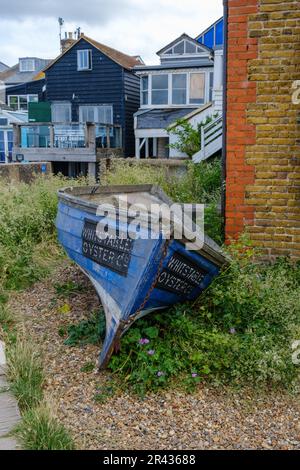 Canoë bleu foncé avec Whitstable Oyster Co. Écrit sur le côté. Whitstable Beach, côte nord du Kent, Angleterre, Royaume-Uni. Banque D'Images