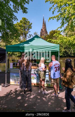 Les gens se rassemblent dans un stand lors du Lichfield Food Festival. La cathédrale de Lichfield est visible en arrière-plan. Banque D'Images