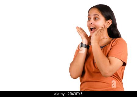 Image d'une jeune femme indienne excitée se tenant isolée sur fond blanc avec Copy Space. Regarder dans l'appareil photo. Banque D'Images